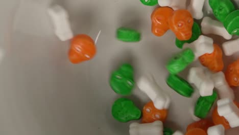 Extreme-close-up-of-bones-and-skulls-shaped-candy-falling-on-a-plate