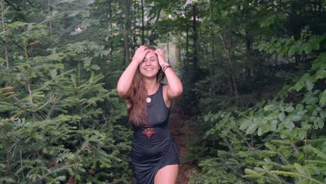 Slow-motion-follow-up-shot-from-front-of-young-happy,-sexy-and-beautiful-girl,-walking-with-a-smiling-face-in-the-middle-of-dense-forest