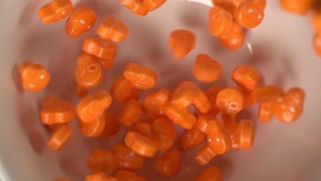 Nahaufnahme-Von-Orangefarbenen,-Schädelförmigen-Süßigkeiten,-Die-Auf-Einen-Teller-Fallen