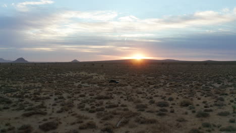 Geländewagen,-Der-Bei-Sonnenuntergang-Einen-Feldweg-In-Der-Mojave-Wüste-Hinunterfährt---Luftbild