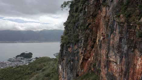Female-rock-climber-ascending-rock-face-precipice,-aerial-view