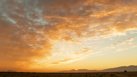 Sich-Schnell-Bewegende-Wolken-Leuchten-Von-Golden-Bis-Rosa,-Während-Der-Sonnenuntergang-über-Der-Mojave-Wüstenlandschaft-Leuchtet