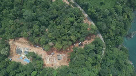 Aerial-drone-birds-eye-view,-slow-left-trucking-shot-of-land-clearing-and-development-in-the-tropical-forest-by-the-coast-on-an-Island-in-Thailand