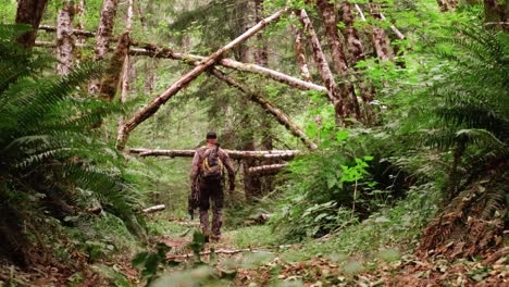 Male-hunter-with-a-bow-walks-through-green-forest