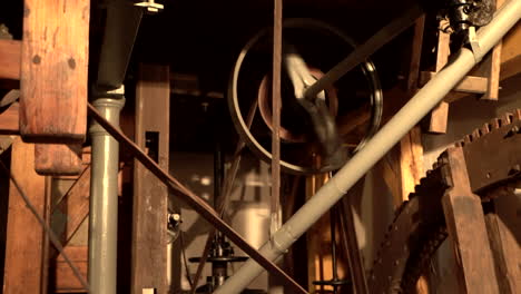 Spinning-Cogwheels-Gear-Wheels-with-transmission-in-wooden-Historical-old-Mill---panning-up-handheld-shot