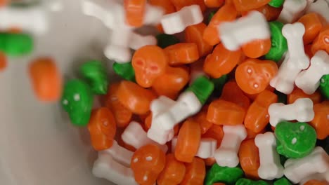 Orange-and-green-skulls-and-bones-shaped-candy-falling-on-a-plate