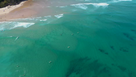 Revealing-drone-shot-of-surfers-riding-waves-at-Wategos-Beach-in-Australia