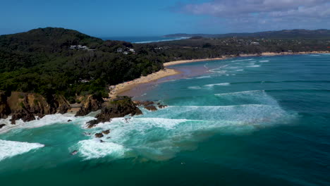 Wide-rotating-drone-shot-of-surfers-in-the-ocean-at-Wategos-Beach-in-Byron-Bay,-Australia