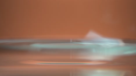 Wassertropfen-Auf-Der-Wasseroberfläche-Auf-Glänzend-Orangefarbenem-Hintergrund-Hautnah