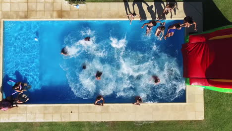 Top-Down-Aerial-View-of-People-Crowd-Jumping-Together-in-Swimming-Pool-on-Sunny-Summer-Day,-High-Angle-Drone-Shot