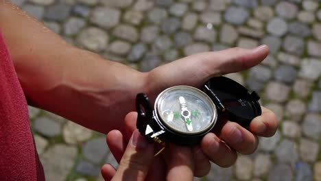 young-man-takes-out-a-compass-and-opens-it,-the-sun-is-reflected-in-it