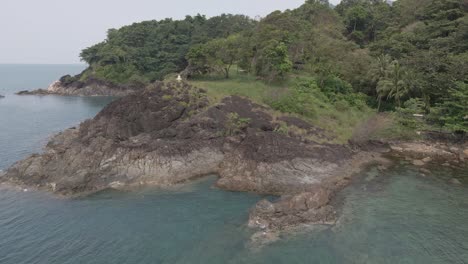 Drone-orbit-shot-,-birds-eye-view-of-granite-rock-coastline-on-a-tropical-Island-with-jungle-lush-green-forest-and-ocean