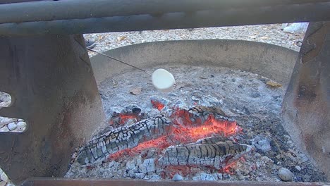 Large-white-marshmallow-roasting-to-a-golden-hue-over-campfire-coals