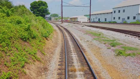 Blick-Auf-Die-Gleise-Hinter-Einem-Zug,-Der-An-Einem-Sommertag-Vorbeifährt