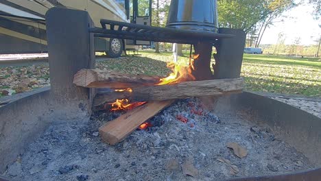 Looping---Three-logs-burning-in-campfire-ring-at-at-campground-with-old-fashion-coffee-pot-perking-above-the-coals