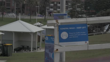 White-Car-Passing-By-Coastal-Walk-With-Social-Distancing-Sign---Bronte-Beach-Coastal-Walk-During-COVID-19---Sydney,-NSW,-Australia