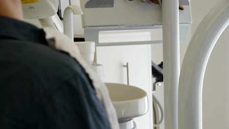 Beim-Zahnarzt-Wird-Ein-Patient-Zum-Spülen-An-Ein-Waschbecken-Gefahren