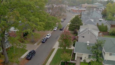 Aerial-of-a-car-driving-away-down-the-street-in-a-suburban-neighborhood-on-an-Autumn-day