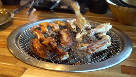 Korean-Barbecue-built-in-grill-in-table-turning-pieces-of-chicken-in-restaurant