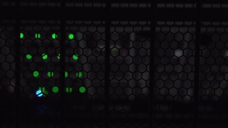 Vertical-view-of-lamp-glowing-in-a-dark-data-cabinet-over-a-storage-server-with-blurred-green-lights