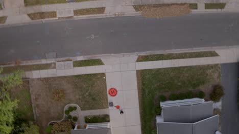 Overhead-view-of-drone-pilot-flying-drone-from-a-suburban-driveway-as-drone-spins-around-over-street