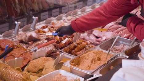 A-gloved-deli-worker-selects-a-portion-of-fresh-cut-meat-from-a-specialty-counter