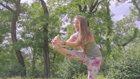 Caucasian-woman-holds-yoga-pose-outdoors-in-nature,-slow-motion-shot