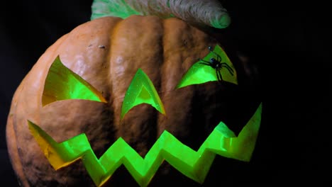 Halloween-pumpkin-with-a-scary-face-and-a-spider-on-the-eye,-illuminated-from-the-inside-multicolored-lights,-a-very-scary-pumpkin-for-Halloween