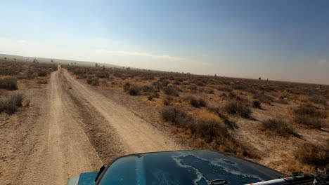 Four-wheel-drive-vehicle-turns-off-a-paved-road-onto-a-dirt-trail-in-the-Mojave-Desert-for-an-adventurous-ride---driver-POV
