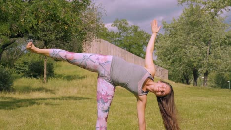 Caucasian-woman-holds-sideways-yoga-pose-in-nature,-slow-motion-tilt