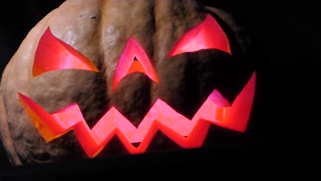 Halloween-pumpkin-with-a-scary-face-and-a-spider-on-the-eye,-illuminated-from-the-inside-multicolored-lights,-a-very-scary-pumpkin-for-Halloween