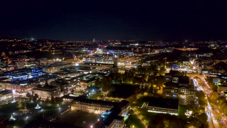 Aerial-night-time-lapse-in-4k-of-downtown-skyline-in-the-city-of-Stuttgart,-Germany-from-left-to-right
