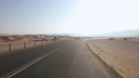 Pan-right-Driving-through-empty-barren-desert-road-to-reveal-incredible-Abu-Dhabi-sand-dunes-on-sunny-day