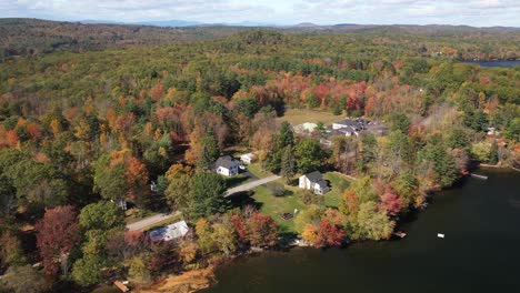 Drone-Aerial-View,-Picturesque-Lakefront-and-Houses-in-Colorful-Forest-on-Sunny-Autumn-Day,-Maine-USA