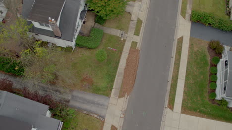 Overhead-view-of-houses-in-suburban-neighborhood-as-drone-descends-for-a-landing-with-the-drone-pilot-in-the-frame