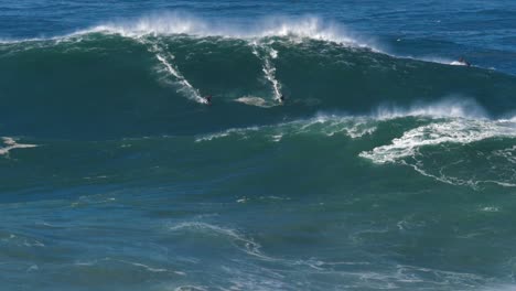 Slow-motion-of-a-big-wave-surfers-sharing-a-monster-wave-in-Nazaré,-Portugal-but-things-go-wrong