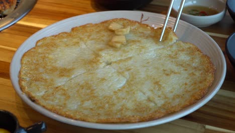 PAJEONE---hands-putting-onion-taking-a-slice-of-traditional-Korean-pizza-made-from-rice-flour-and-vegetables