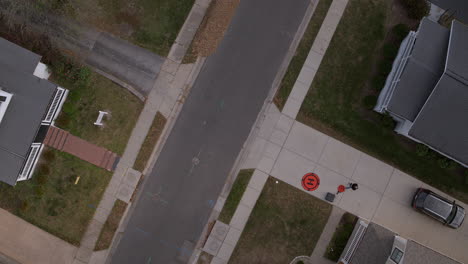 Overhead-view-of-drone-pilot-in-driveway-in-the-suburbs-with-a-tilt-up-to-the-sky-and-on-horizon-while-descending
