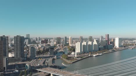 Drone-footage-of-a-slow-right-pan-of-the-city-of-Rotterdam,-Netherlands-and-it's-water-channel-on-a-sunny-day