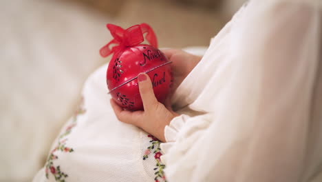 slow-motion-shot-Over-the-shoulder-of-kid-in-a-Christmas-white-dress-holding-a-red-bauble---close-up