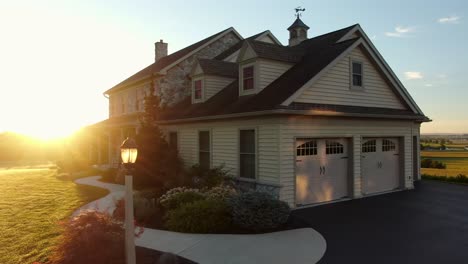 Dramatic-sunrise-illuminates-large-stone-farm-house-with-green-front-yard