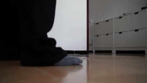 Video-of-a-bearded-man-sweeping-his-living-room's-floor-with-a-black-and-green-broom
