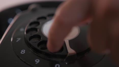 Close-up-of-the-dialing-wheel-of-a-rotary-phone-as-a-person-dials-a-number