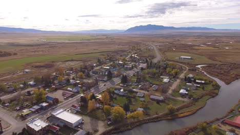 Kleine-Stadt-In-Montana-Entlang-Des-Flusses-Im-Wunderschönen-Sonnenuntergangslicht-Des-Herbstes,-Drohnenaufnahme,-Zwillingsbrücken