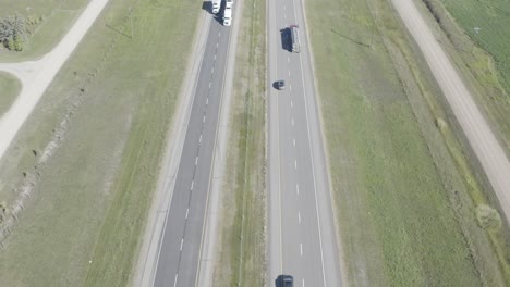 aerial-birds-eye-view-dolly-roll-over-a-the-interstate-highway-as-theres-a-grass-field-divider-between-2-lanes-on-each-side-headed-east-or-west-or-north-or-south-on-a-sunny-summer-day-by-farms-HWY2-2