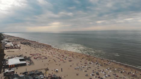 Aerial-footage-flying-over-a-coastline-beach-of-the-city-of-Zandoort,-Netherlands-along-the-North-Sea
