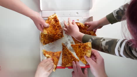 Hands-grabbing-slices-of-pizza-from-a-pizza-box