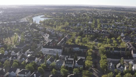 aerial-fly-over-inverness-elgin-hills-south-east-calgary-alberta-during-sunrise-on-a-hot-summer-morning-in-Canada-where-the-residential-community-resembles-brick-homes-of-Scotland-in-the-UK-Britain