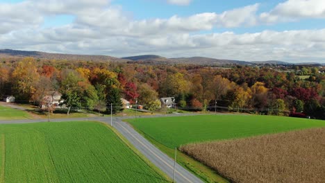 Rising-reveal-shot-of-rural-American-farmland,-homes,-lake-during-autumn-harvest-season