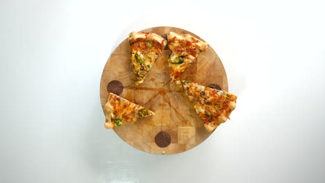 Hands-grabbing-slices-of-pizza-from-a-pizza-wheel-board